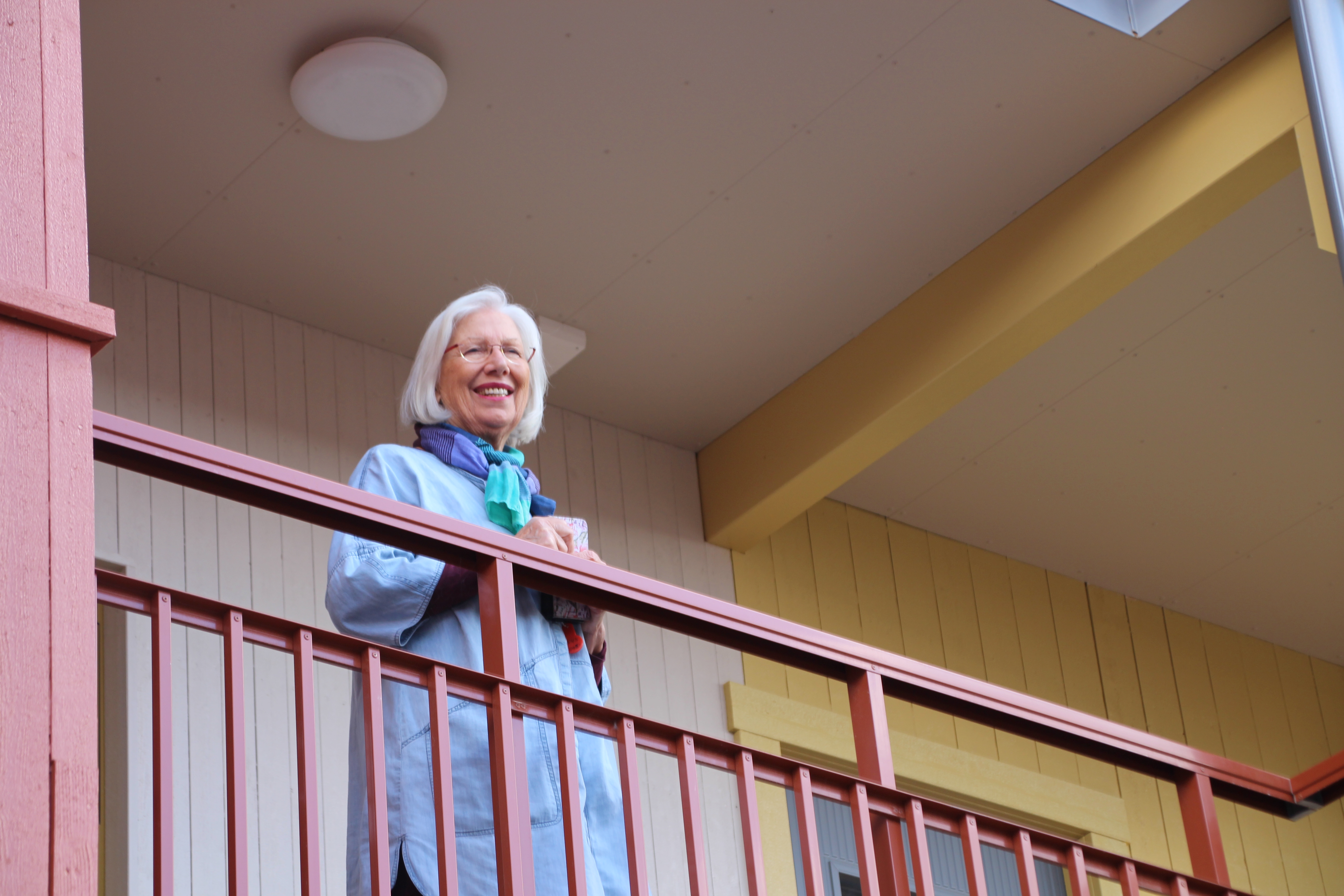 En kvinna står på loftgången på ett flerbostadshus på Broby station. 
